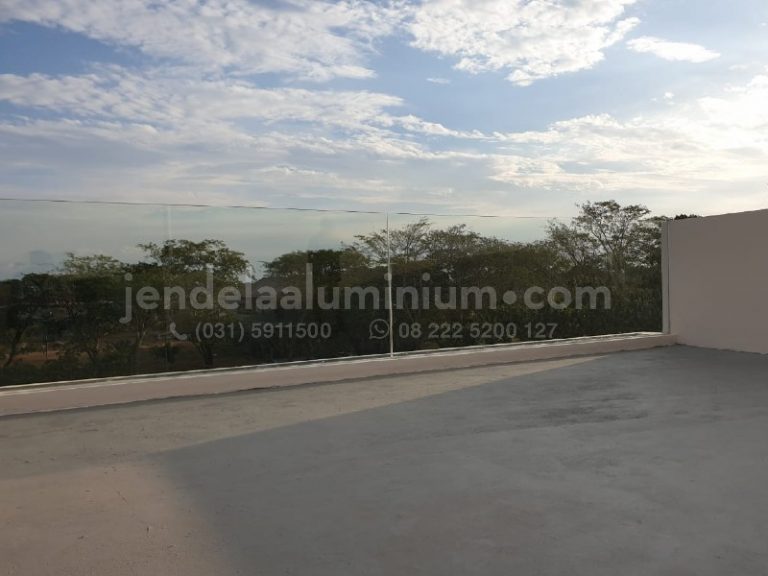 Balkon rumah modern dengan railing kaca tempered frameless di Citraland Surabaya.